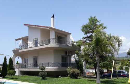 a white house with a balcony and a tree at Villa Oneiro in Kanali