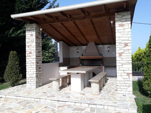 an outdoor kitchen with a picnic table and a grill at Villa Oneiro in Kanali