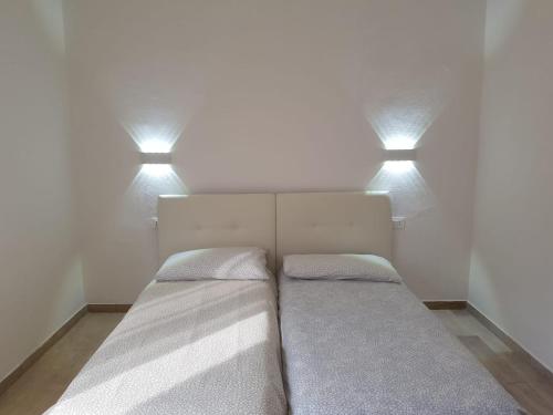 two beds in a room with two lights above them at Eagle Rooms in Riva del Garda