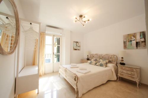 biała sypialnia z łóżkiem i lustrem w obiekcie Casa Volare- estilo y relax en pleno casco antiguo w Maladze