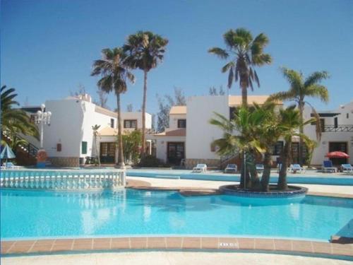 duży basen z palmami i budynkami w obiekcie Canary Islands getaway w mieście Caleta De Fuste