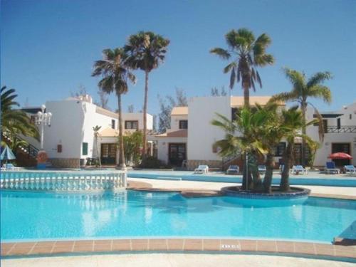 a large swimming pool with palm trees and buildings at Canary Islands getaway in Caleta De Fuste