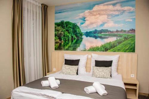 a bedroom with a large painting of a river at Erzsébet Hotel in Csongrád