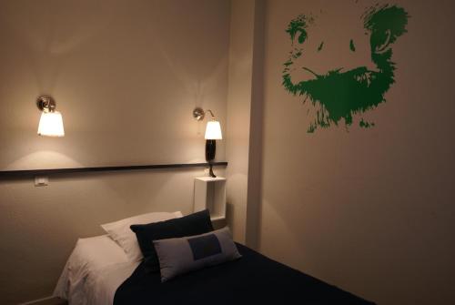 a bedroom with a bed with a green painting on the wall at Hotel de la Placette Barcelonnette in Barcelonnette
