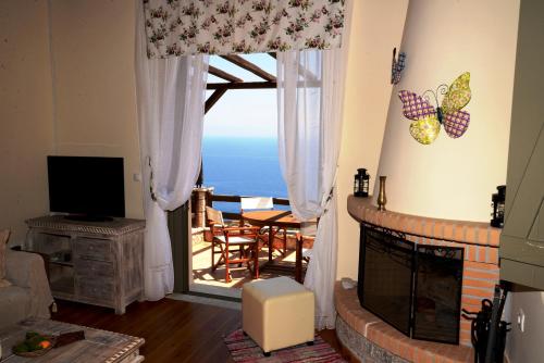 a living room with a fireplace and a view of the ocean at Dio Guesthouses in Leonidion