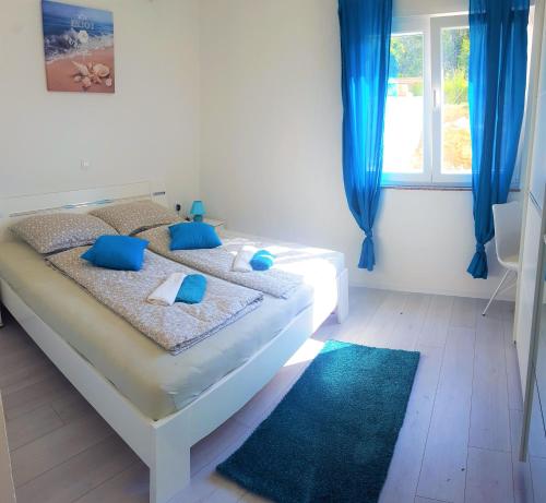a bedroom with a bed with blue pillows and a window at Apartmani "Sandro" Gonar in Rab
