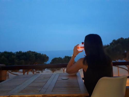 a woman sitting on a deck drinking a glass of wine at Marina Mar in Platja  d'Aro