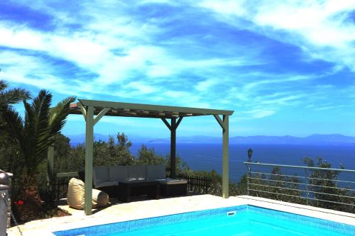 a swimming pool with a pergola and a view of the ocean at Dio Guesthouses in Leonidion