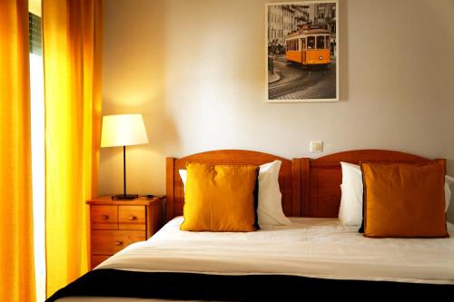 a bedroom with a bed with orange pillows and a train at Oasis Beach Apartments in Luz