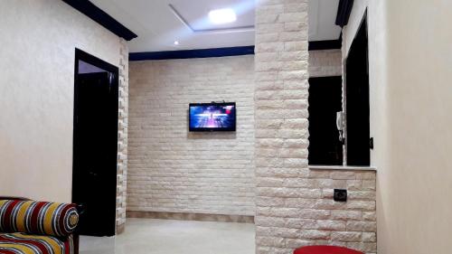 ein Wohnzimmer mit einem TV an einer Backsteinwand in der Unterkunft Joudia in Temara