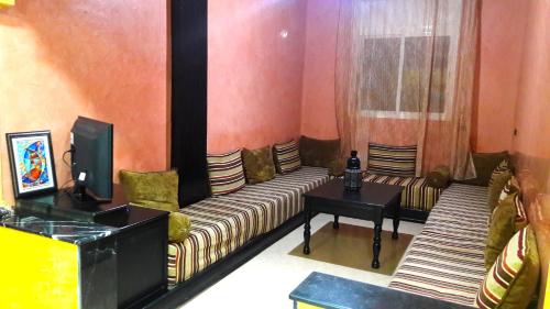 Una sala de estar con un sofá y un televisor. en Joudia, en Temara