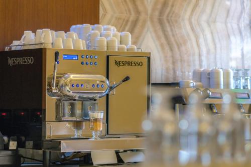 a coffee making machine with cups on a table at Bayat Hotel in Khamis Mushayt