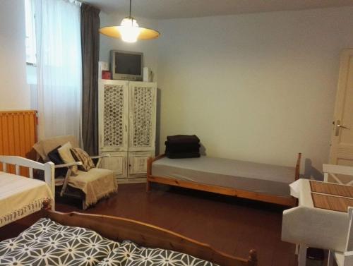 a room with two beds and a tv and a chair at Népkerti Vendégház in Miskolc