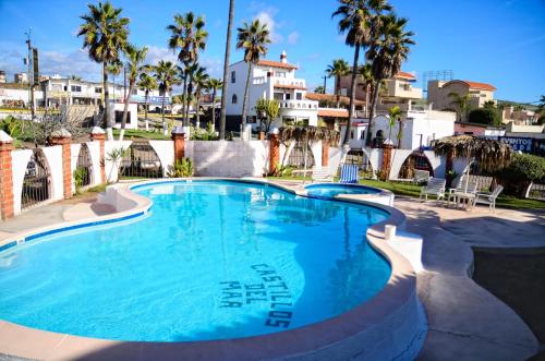 a large swimming pool with palm trees and houses at Castillos Del Mar in Rosarito