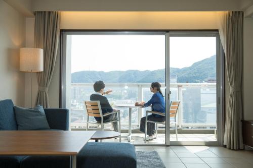 two people sitting at a table in front of a window at Hakodate Danshaku Club Hotel & Resorts in Hakodate