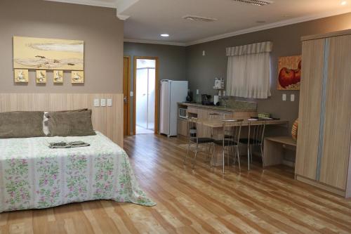 a bedroom with a bed and a kitchen with a table at Solar do Centro in Gramado