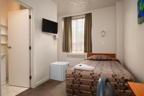 a hotel room with a bed and a television at Kiwi International Hotel in Auckland