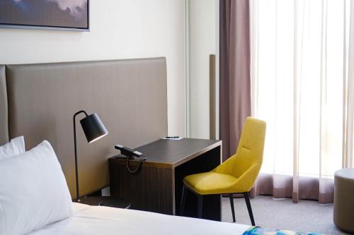a hotel room with a desk and a yellow chair at Mantra Albury in Albury