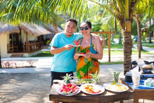 a man and a woman standing next to a table with food at Island View Bar & Bungalow in Gili Air