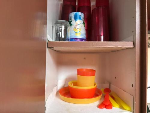 a shelf with bowls and other toys in a cabinet at Gonzales Cozy Little Bear Cabin in Ruidoso