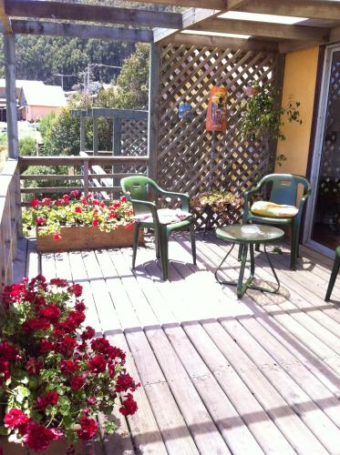 a patio with two chairs and a table and flowers at Cabañas del Rio - La Pesca - Region del Maule in Iloca