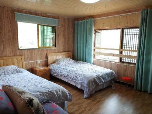 a bedroom with two beds and two windows at Xiasi Ancient Town Yang Gou Guesthouse in Xiasi