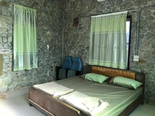 a bedroom with a bed with green curtains at Farm stay 1000 Chang Valley in Ban Chak Phai