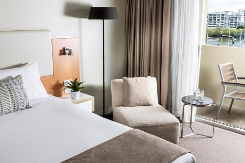 a hotel room with a bed and a chair at Grand Hotel and Apartments Townsville in Townsville