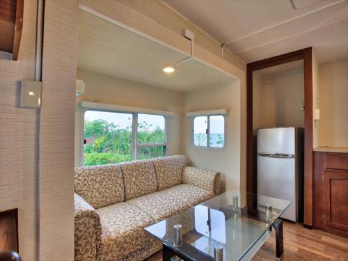 a living room with a couch and a glass table at Wood Pecker Nakijin in Nakijin