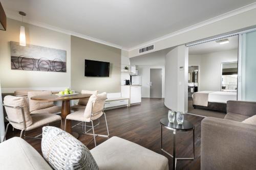 a living room with a bed and a dining room at Grand Hotel and Apartments Townsville in Townsville