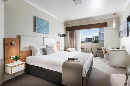 um quarto de hotel com uma cama e uma secretária em Grand Hotel and Apartments Townsville em Townsville