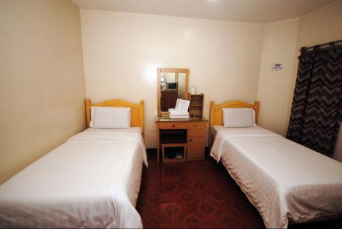 una camera d'albergo con due letti e uno specchio di Hotel 45 Extension a Baguio