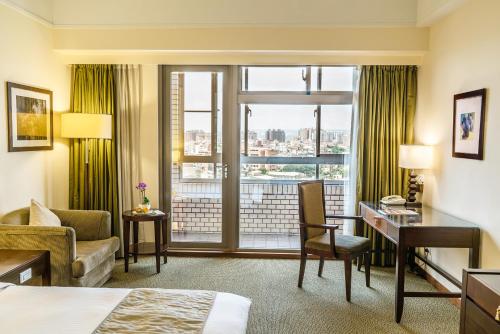 Cette chambre comprend un lit, un bureau et une fenêtre. dans l'établissement Fullon Hotel Jhongli, à Zhongli