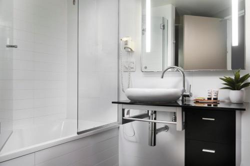 a white bathroom with a sink and a shower at Grand Hotel and Apartments Townsville in Townsville