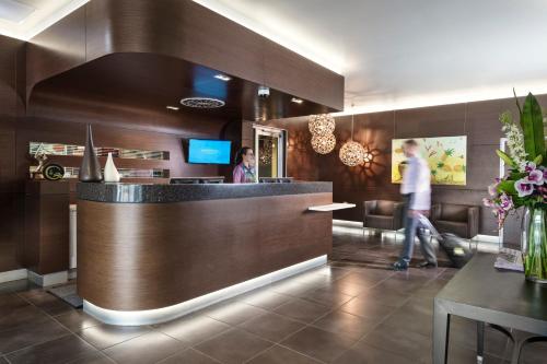 a lobby of a restaurant with a woman standing at a counter at Grand Hotel and Apartments Townsville in Townsville