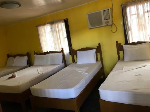 two twin beds in a room with two windows at Luis Bay Travellers Lodge in Coron