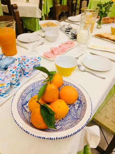 a table with a plate of oranges on it at Hotel Villaggio Ristorante Pizzeria Museo TANIT in Carbonia