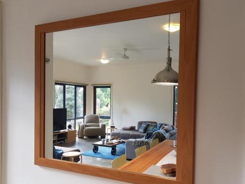 a mirror reflection of a living room with a couch at Bay Breeze Beach Holiday Home in Corinella