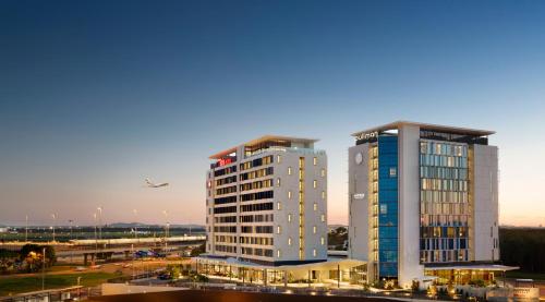 two tall buildings with an airplane flying in the sky at ibis Brisbane Airport in Brisbane