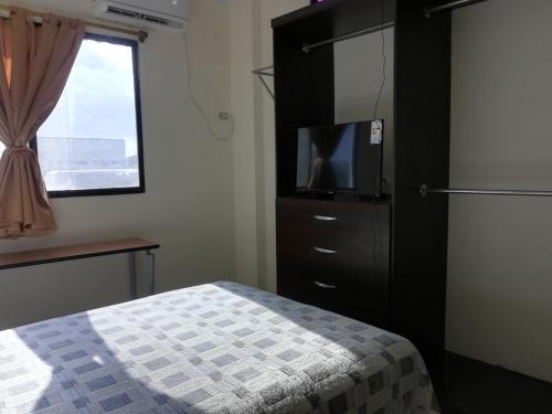 1 dormitorio con 1 cama y vestidor con TV en Alojamiento Castelnouvo, Entre Ríos, Guayaquil, Ecuador, en Guayaquil