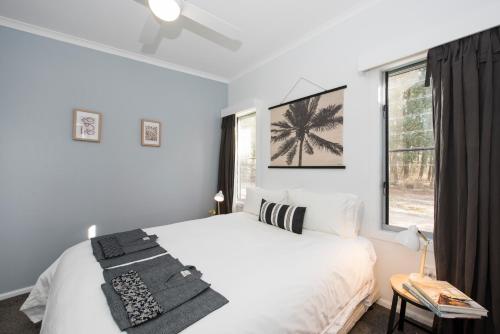 ein weißes Schlafzimmer mit einem Bett und einem Fenster in der Unterkunft Peppertree Farm Mudgee in Mudgee