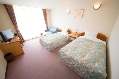 a hotel room with two beds and a television at Senjoen in Shimokō