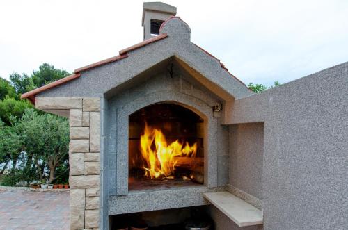 a stone pizza oven with a fire in it at Villa Lidija in Omiš