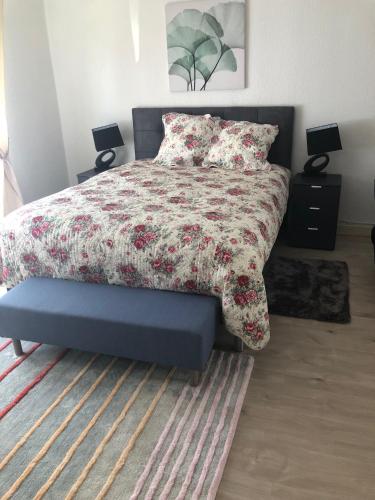 a bed with a floral comforter and a blue bench in a bedroom at Les Charmantes in Cernay