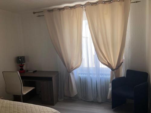 a bedroom with a bed and a desk and a window at Les Charmantes in Cernay