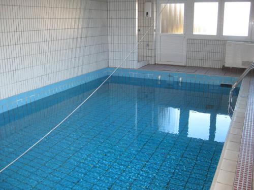 a swimming pool with a blue tile floor and a swimming pool at direktamstrand-sylt in Westerland (Sylt)