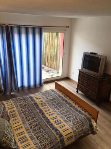 - une chambre avec un lit, une télévision et une fenêtre dans l'établissement Naciento, à Bagnères-de-Bigorre