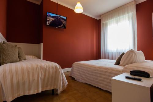 a hotel room with two beds and a window at Hotel Bardolino in Bardolino