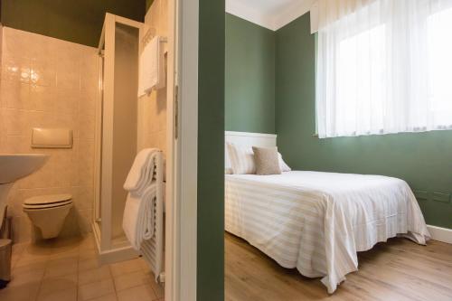 Hotel Bardolino في باردولينو: غرفة نوم بسرير وحمام مع حوض