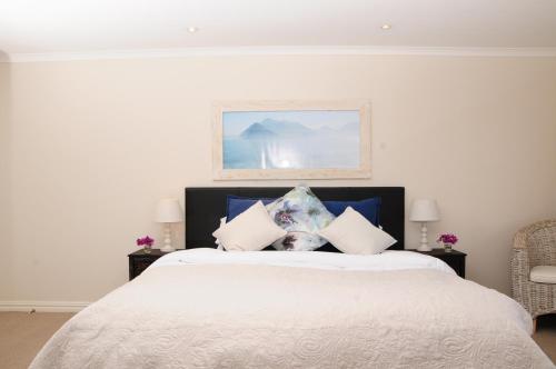 a bedroom with a large bed with white sheets and pillows at Hout Bay Breeze Guest House in Hout Bay